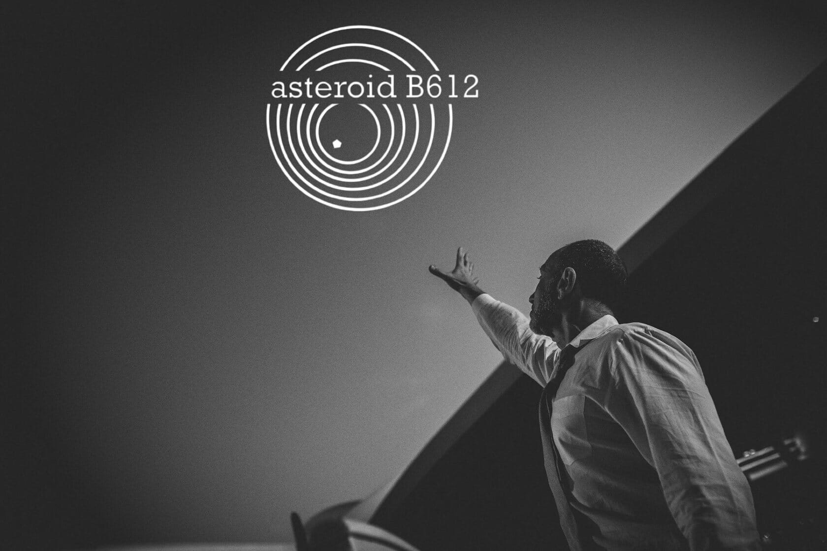 Roman Freud reaching up toward the asteroid B612 logo