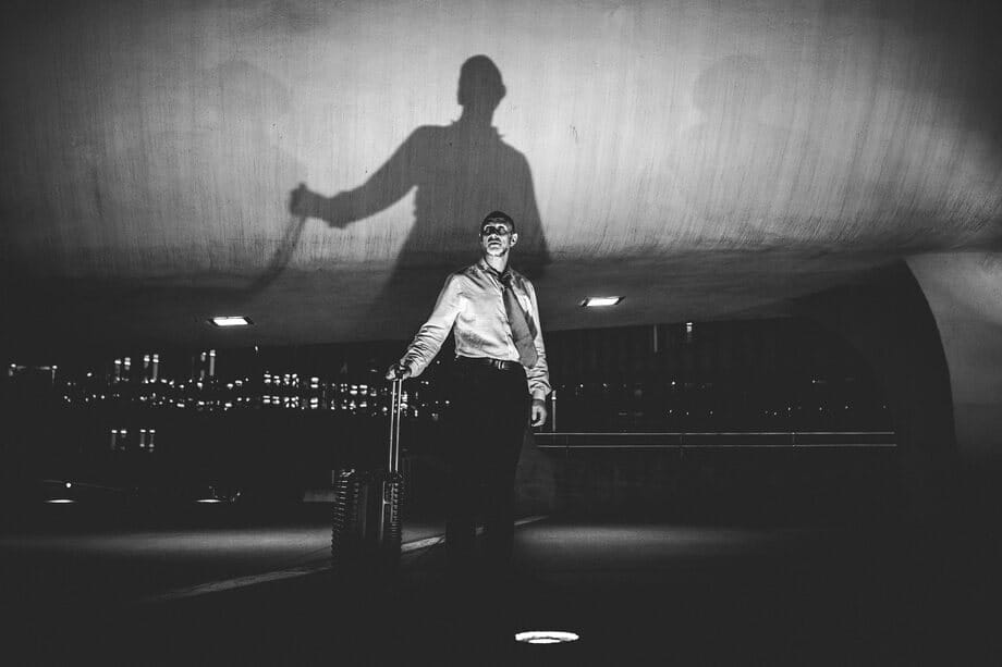 Roman Freud with a suitcase, his shadow cast large on the wall behind him