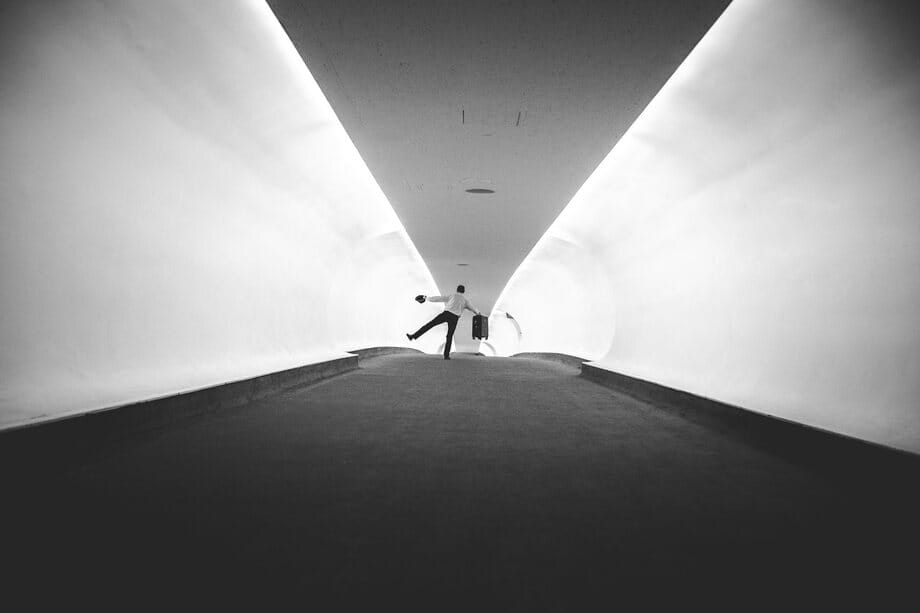 A lone traveler in a long white airport tunnel
